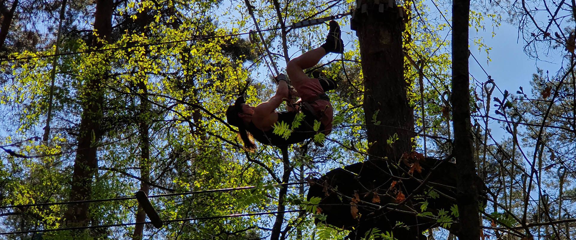 Scout hangt aan kabel tussen de bomen